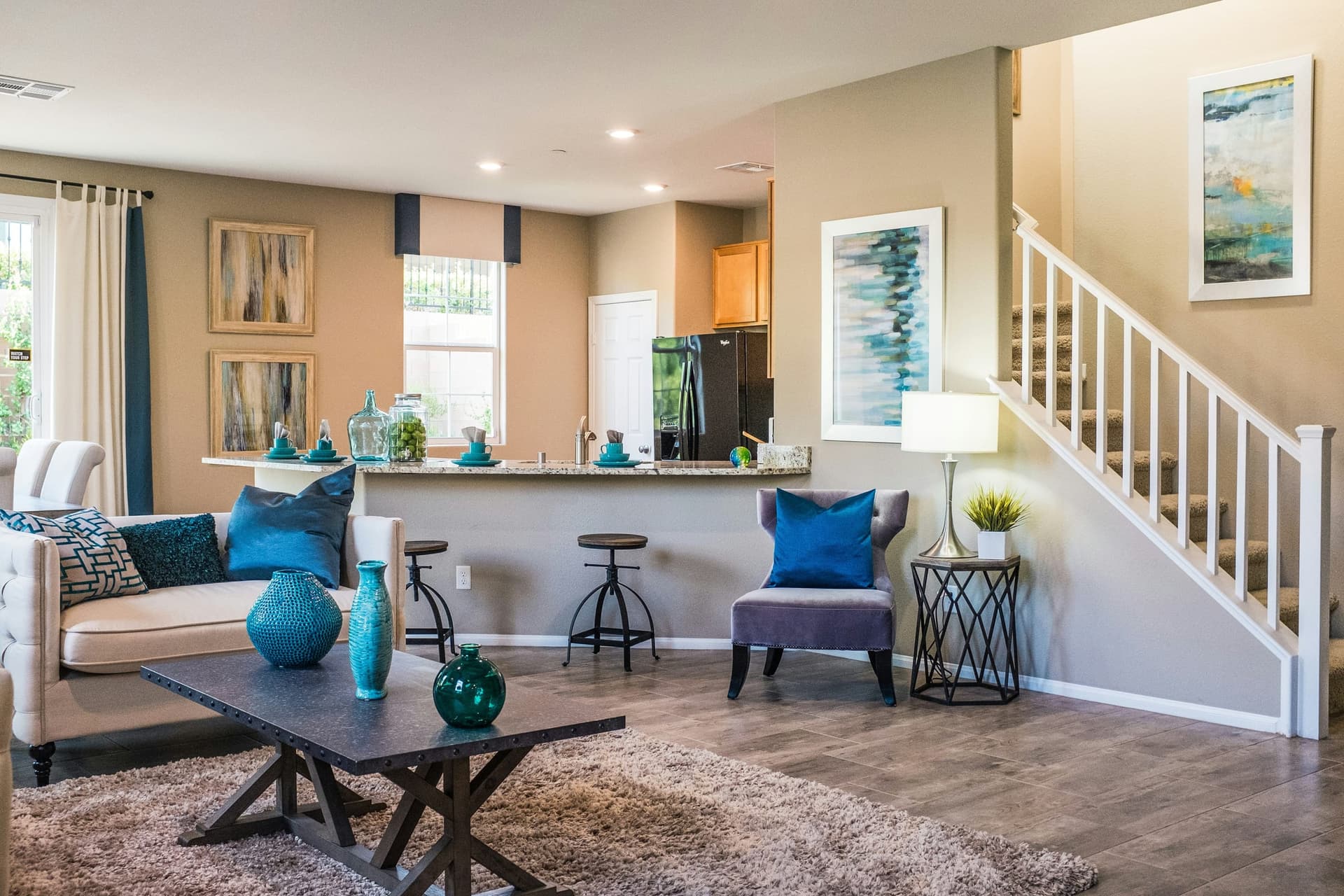 A bright, staged manufactured-home living room with an open kitchen and staircase